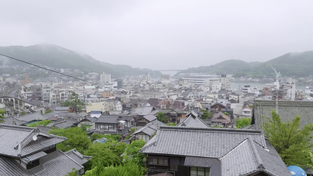 Beautiful slow motion pan high above across Onomichi city on cloudy day