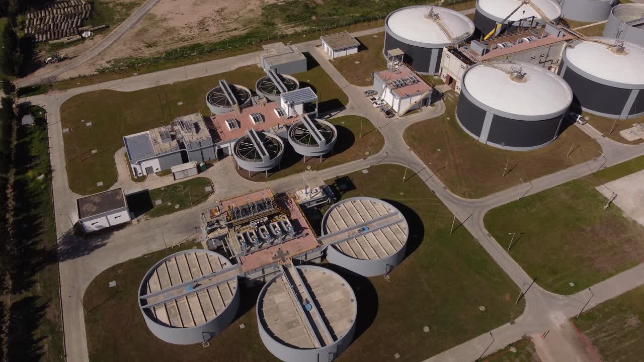 toma aérea de arriba hacia abajo de una gran planta industrial de purificación de agua con tanques y piscinas en buenos aires - almacenamiento, ecosistema de lodos en argentina