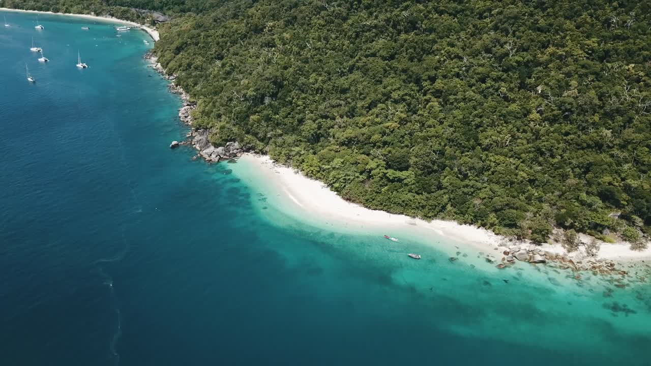 푸른 물 위에 보트가 있는 섬의 열대 백사장 해변을 보여주기 위해 앞으로 나아가는 드론 공중