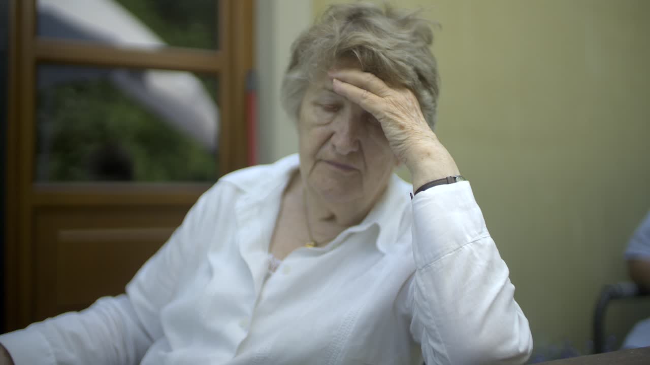 mujer mayor con la mano en la cara pensando, preocupada y triste