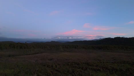Sunset view of Mt. Aoraki from New Zealand’s West Coast, stunning silhouette and warm evening colors, aerial pullback over plains