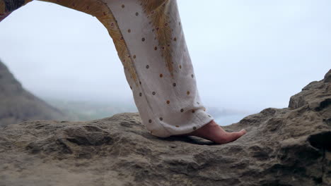 On-a-rocky-seashore-at-sunset,-a-young-woman-engages-in-yoga,-underlining-a-healthy-lifestyle,-harmony,-and-the-interconnection-between-humans-and-nature,-with-the-blue-ocean-as-the-backdrop