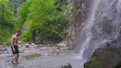 Sportlicher,-Oben-Ohne-Mann,-Der-Auf-Den-Wasserfall-Zugeht.