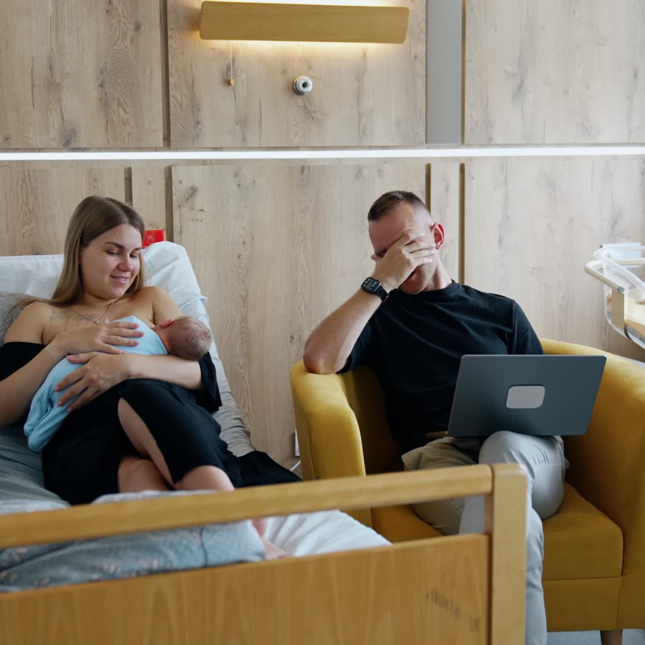 New-made parents having a little argument. Man with laptop in hands speaking to a wife breastfeeding a newborn