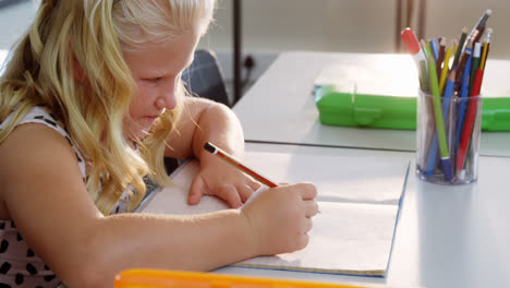 schoolgirl doing homework in classroom