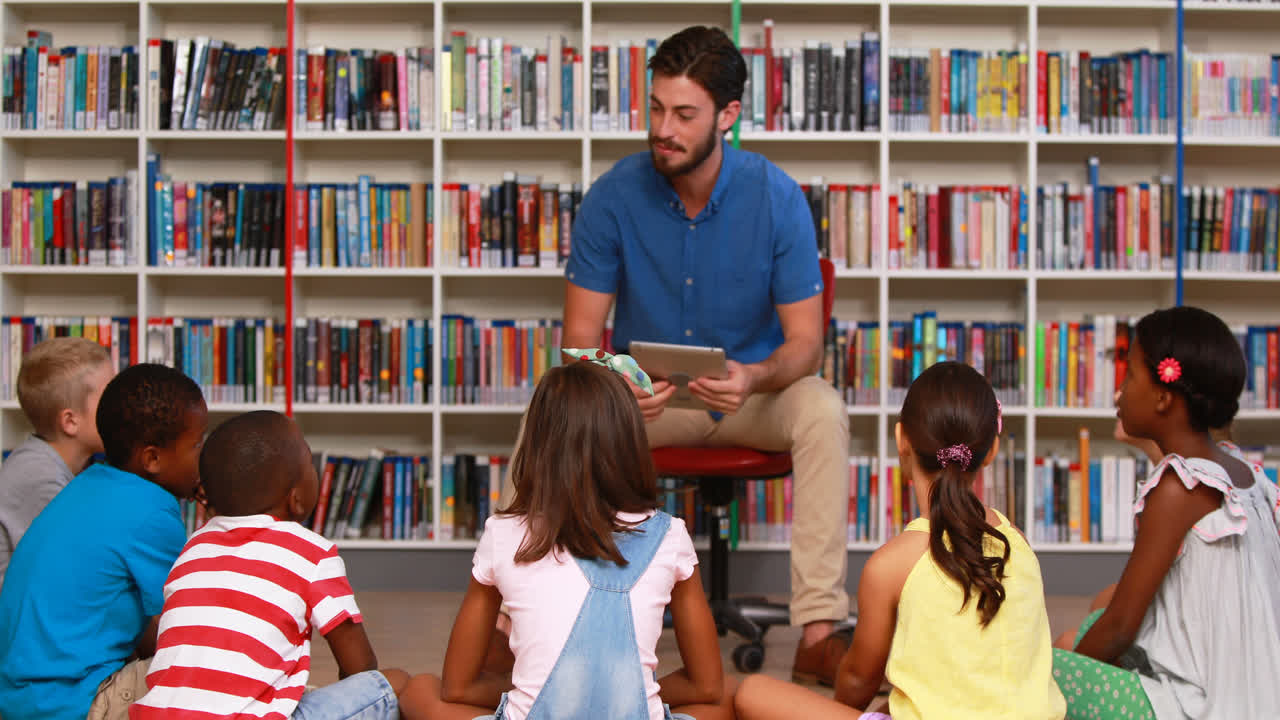 maestro enseñando a los niños en una tableta digital en la biblioteca