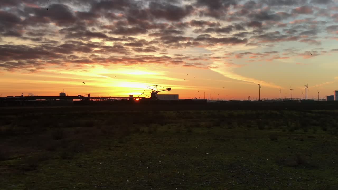Industry under a beautiful sky. Sunrise behind a coal terminal stacker