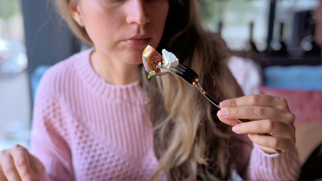 Woman eating a fig salad with nuts and cheese at a restaurant