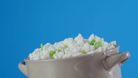 bowl with cottage cheese and green onion slowly rotates.