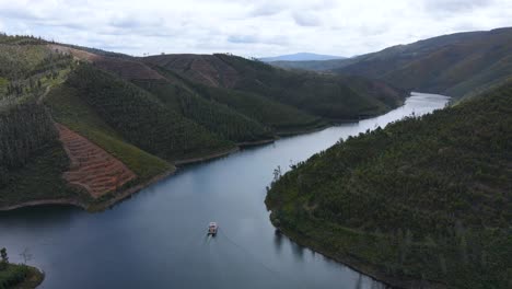 aerial view of a solar boat travelling between pinewood valleys on a sunny day