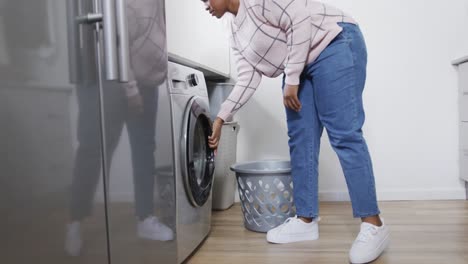 Afroamerikanische-Frau-Legt-Kleidung-In-Die-Waschmaschine,-Wäscht-Zu-Hause-Wäsche,-Zeitlupe