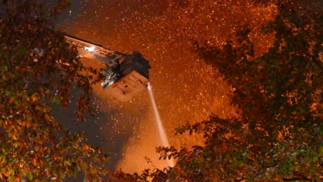 Firefighters-extinguishing-large-fire-from-above-on-a-crane,-many-sparks