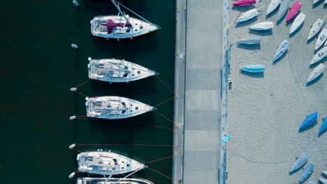 Aerial-view-of-sailboats-moored-next-to-a-dock-with-covered-dinghies-on-land