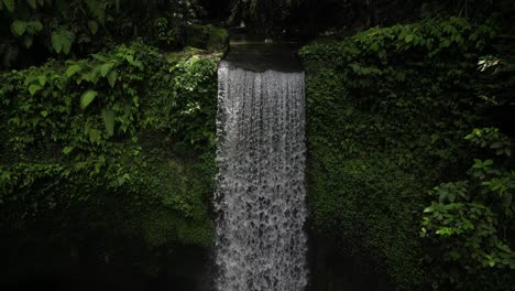 A-peaceful-aerial-perspective-of-Tibumana-waterfall-in-Bali,-Indonesia-on-a-sunny-afternoon