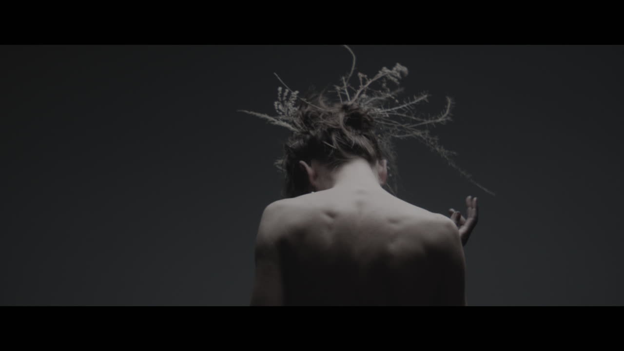 Uma mulher vestida como mãe natureza move-se lentamente em um movimento de dança