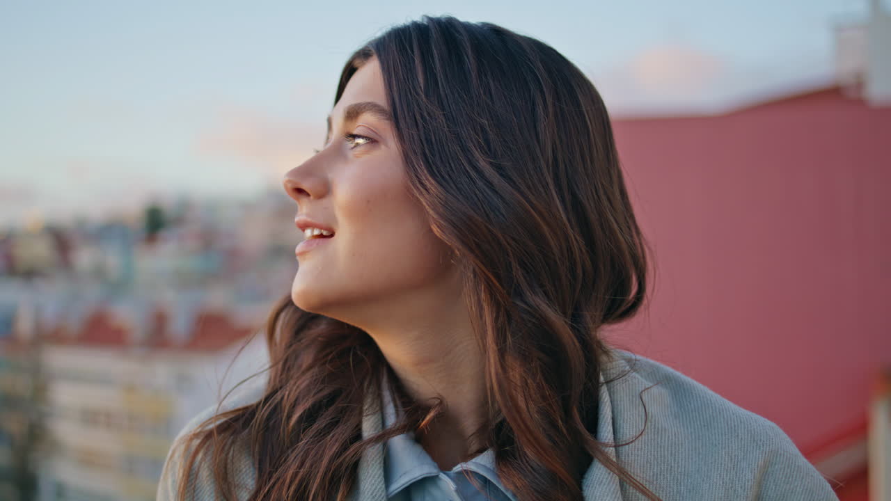 mujer feliz de pie en el tejado del paisaje urbano en el cielo al atardecer de cerca. dama descansando