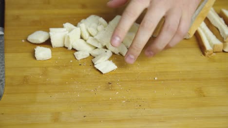 Chef-adds-pepper-and-alt-spices-onto-bread-pieces-for-Caesar-salad-on-wooden-cut-board