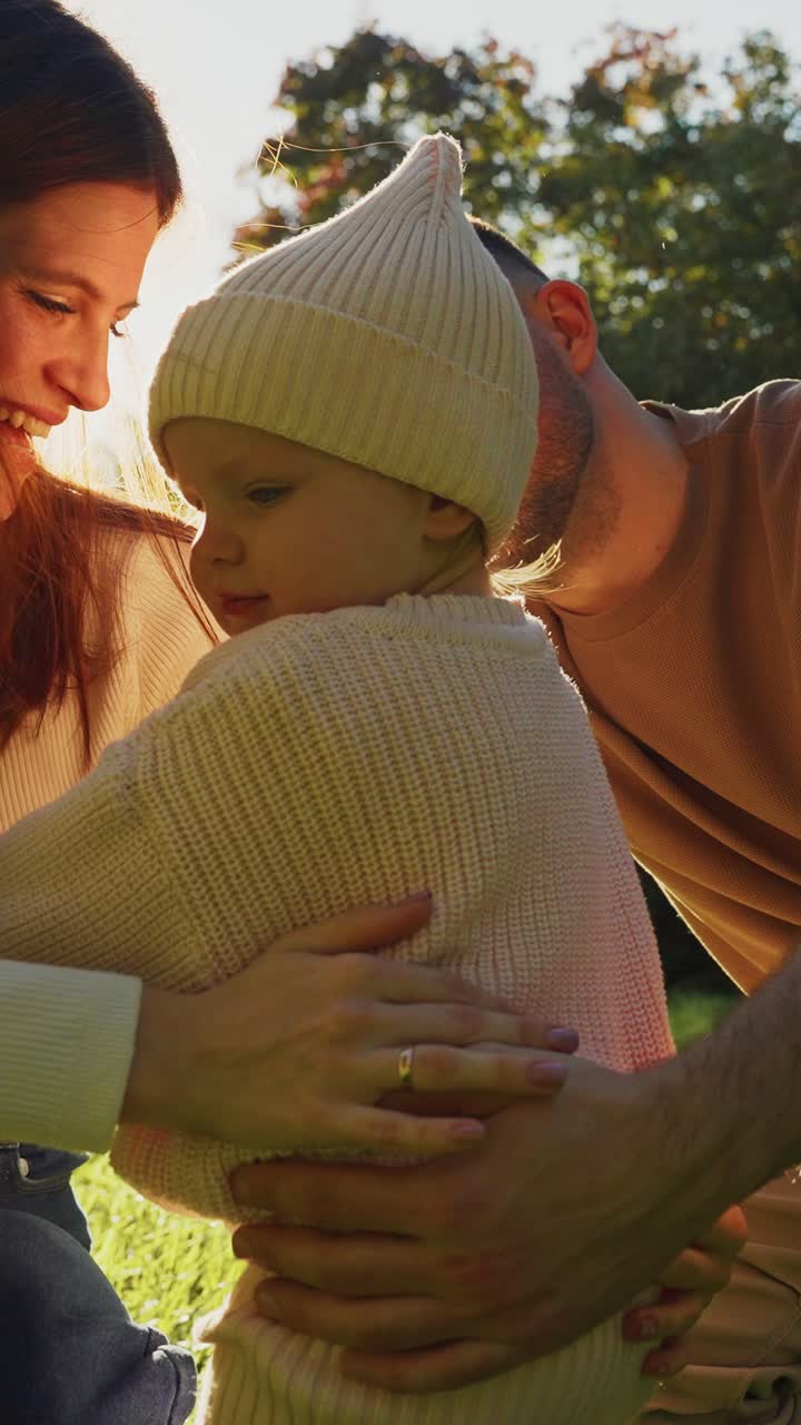 Happy Parents Supporting Their Baby's First Steps in a Sunny Park