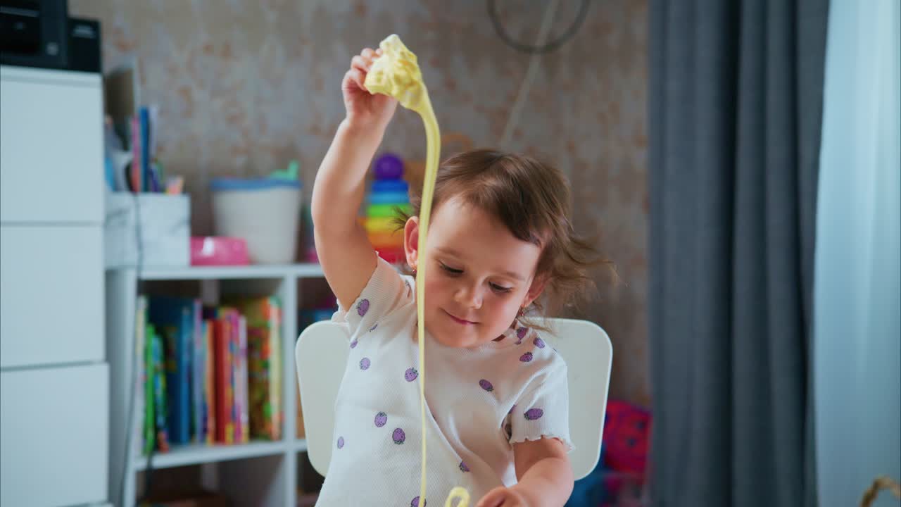 A Delightful Playtime Experience: A Little Child Engages with Colorful, Stretchy Slime While Exploring Creativity and Joy in a Fun-filled Environment