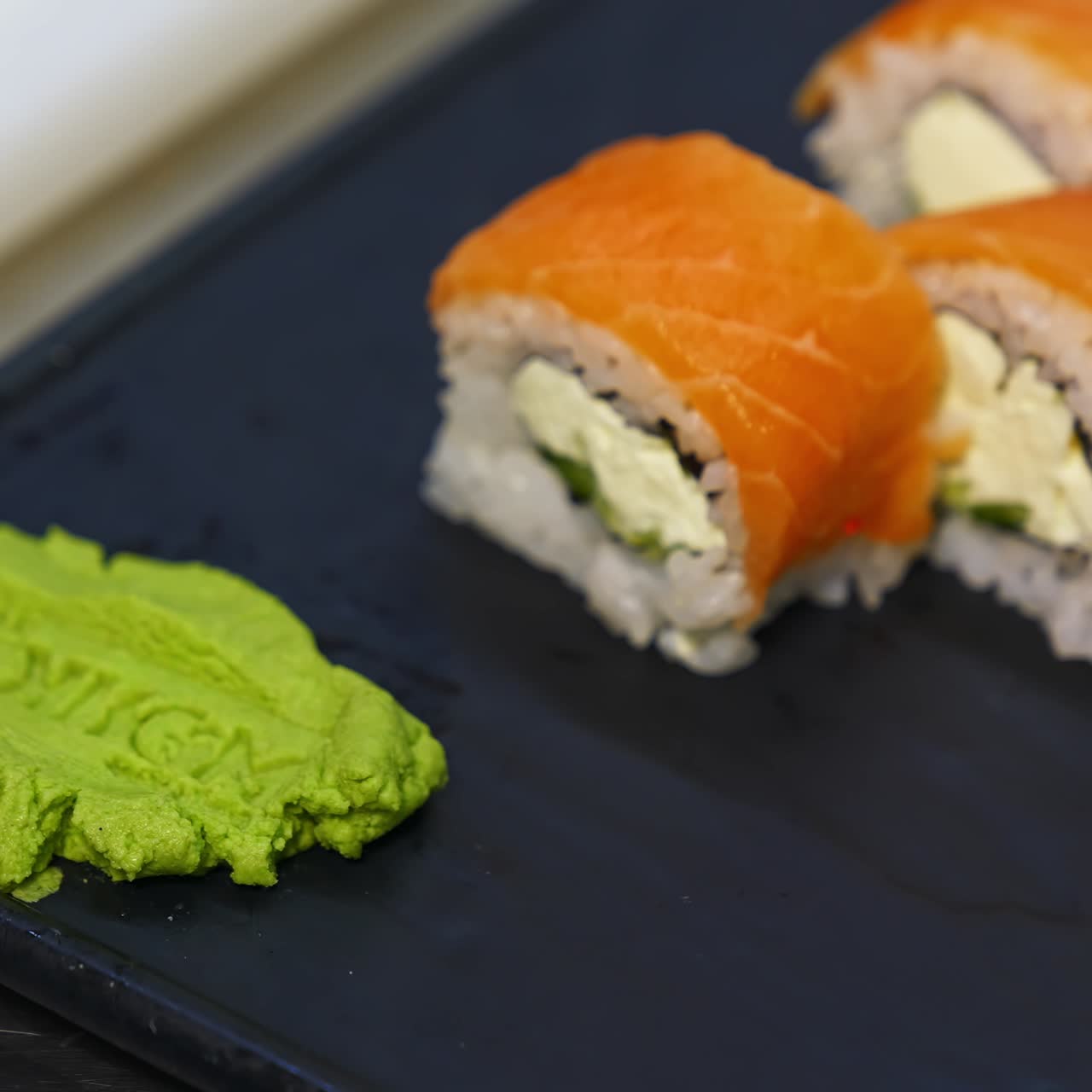 Sushirullasetti mustalla liuskekivitaustalla. Erilaisia japanilaisia sushiruokia ravintolassa. Setti sisältää lohta, tonnikalaa, kasviksia, lentokalan mätiä ja kaviaaria lähikuvassa. Japanilaisen ravintolan ruokalista.