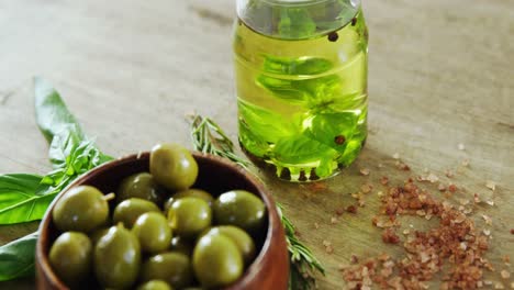 green olives, olive oil and herbs on table