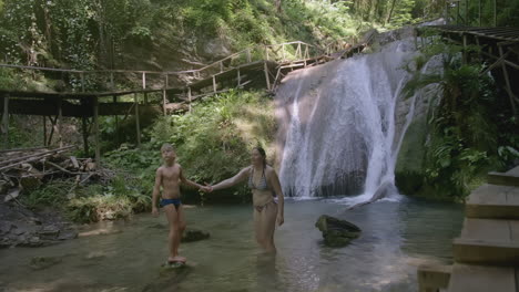 madre y hijo disfrutando de una cascada en un bosque exuberante