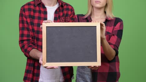 young couple holding blackboard together