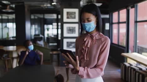 Mujer-Asiática-Con-Mascarilla-Usando-Tableta-Digital-En-La-Oficina-Moderna