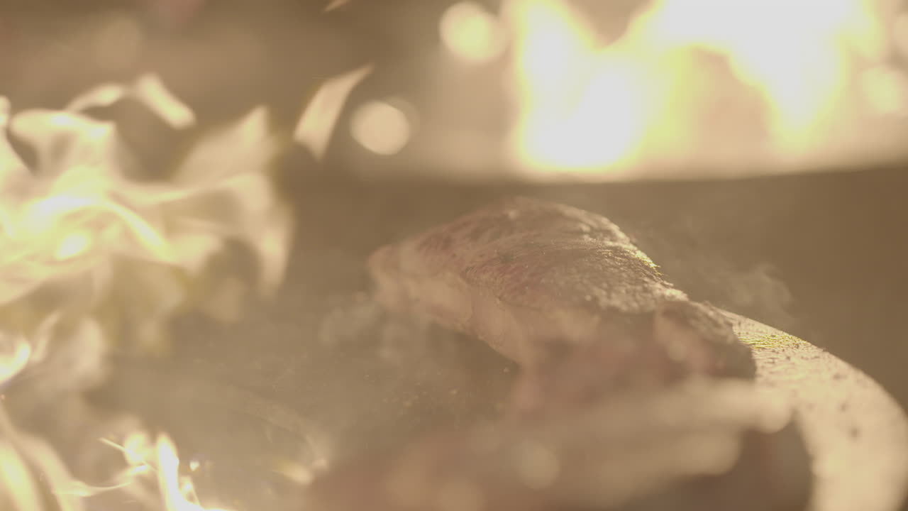 Slowmotion of a juicy steak getting baked on a hot plate with grease burning away creating smoke LOG