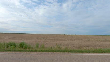 a big sky and plowed fields are evident in this roadside drive