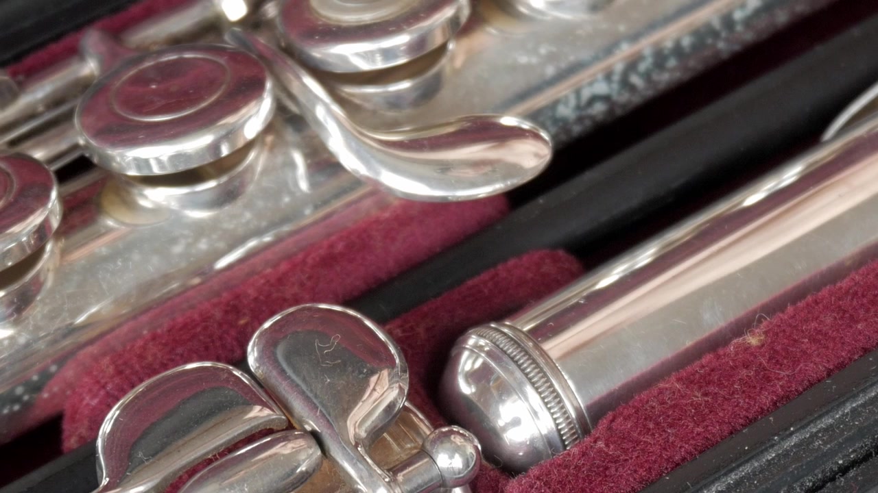 Closeup of shiny silver flute in a lined case, showing detailed keys and headjoint