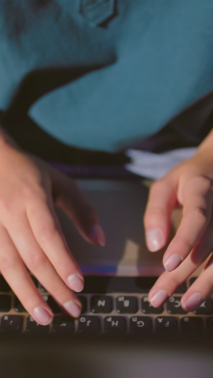 primer plano de las manos de una mujer escribiendo en una computadora portátil al aire libre por la noche, el reflejo de la pantalla ilumina sus dedos mientras trabaja en un banco con una bolsa roja cerca
