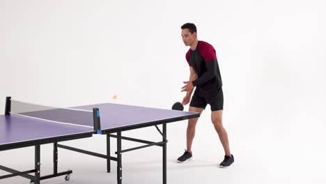 playing table tennis, man hitting ball with paddle in studio setting