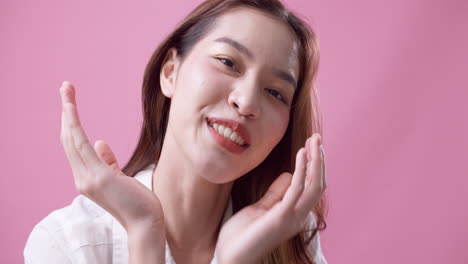 스튜디오에서 분홍색 배경에서 손을 흔드는 즐거운 아름다운 백인 젊은 여성