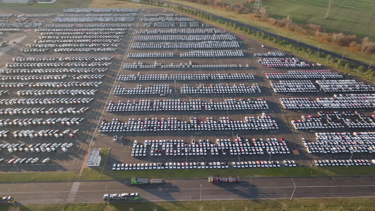 Aerial landscape over vast parking lot with vehicles ready to be shipped,
