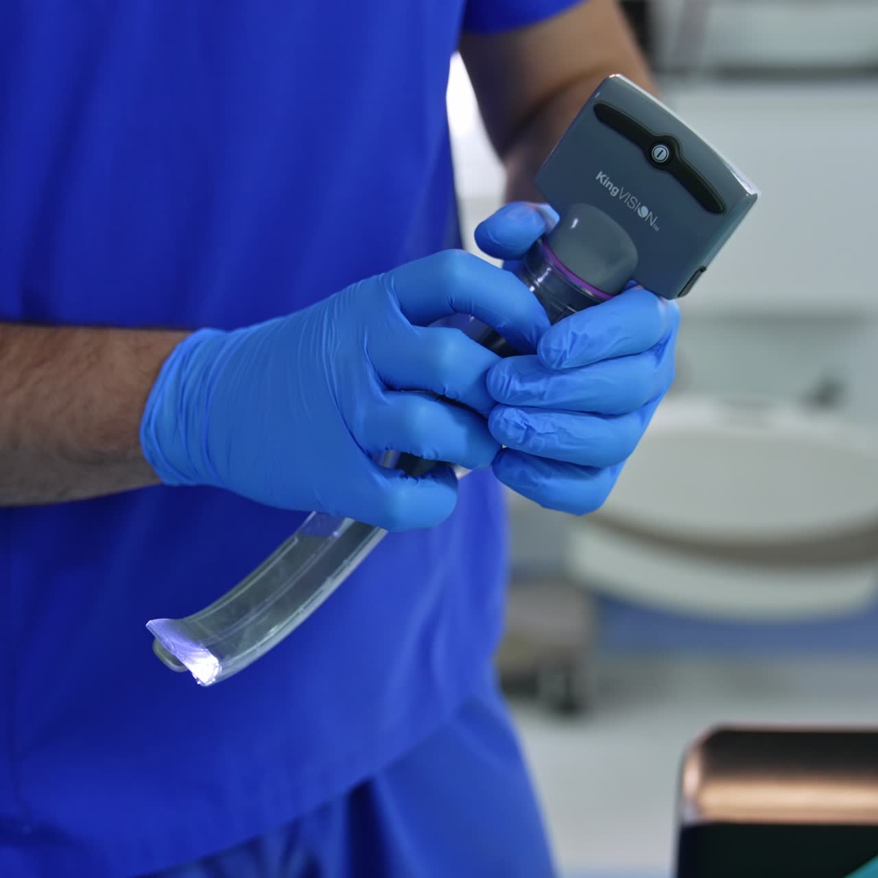 Male hands in latex gloves hold the modern portable video laryngoscope. Close up. Anesthesiologist demonstrating the equipment for intubation