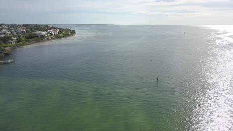 Tiro-De-Drone-De-Rotación-De-Paddle-Boarder-En-El-Océano-Hacia-La-Puesta-De-Sol