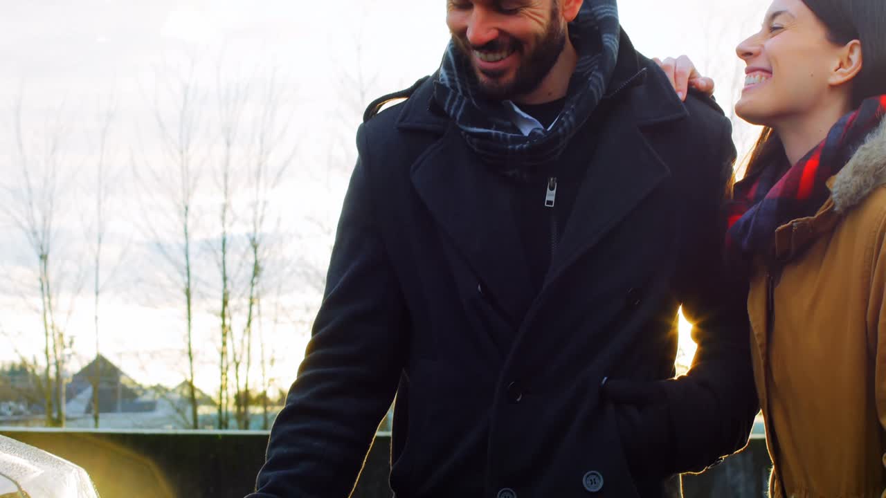 pareja hablando mientras carga el coche eléctrico en un día de invierno