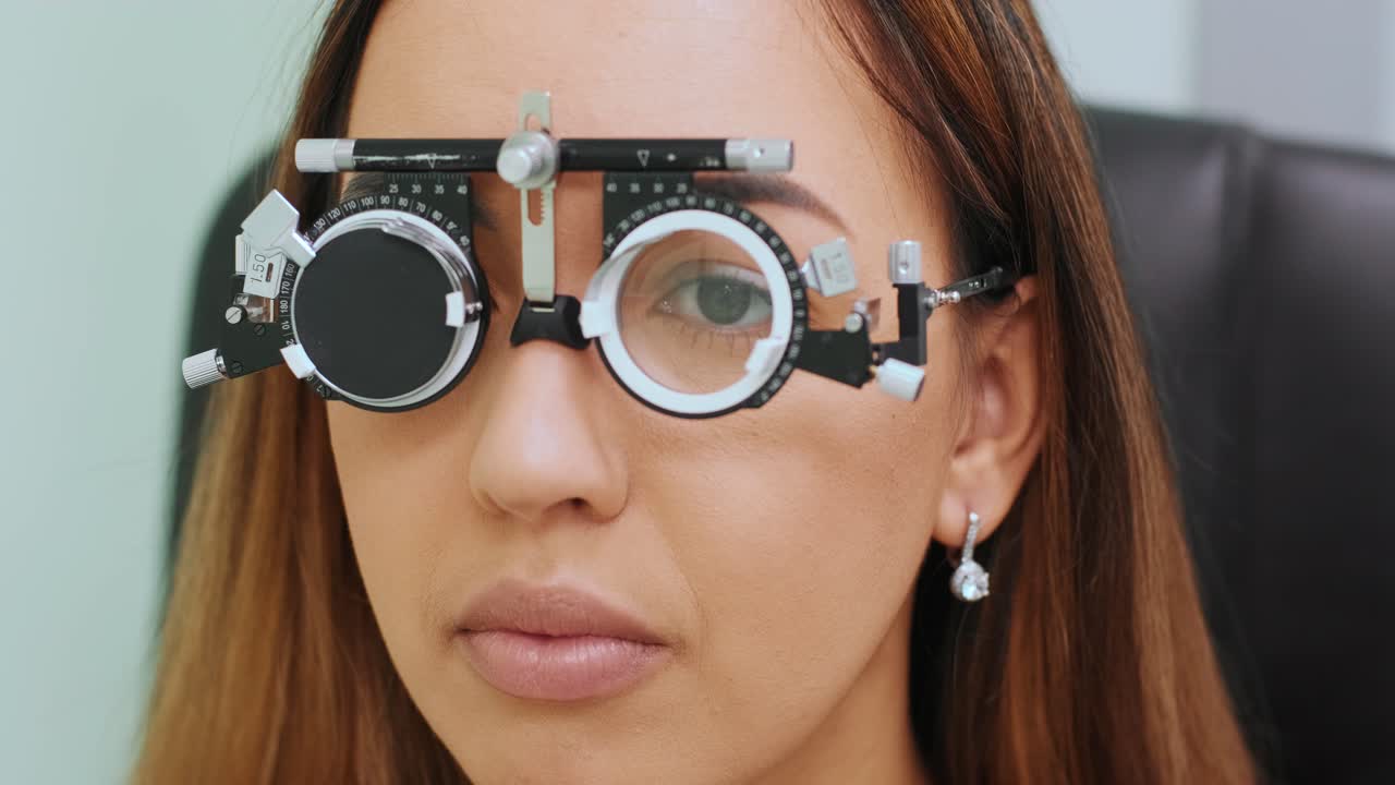 optometrista masculino con marco de prueba comprobando la visión de una mujer hermosa en la clínica ocular