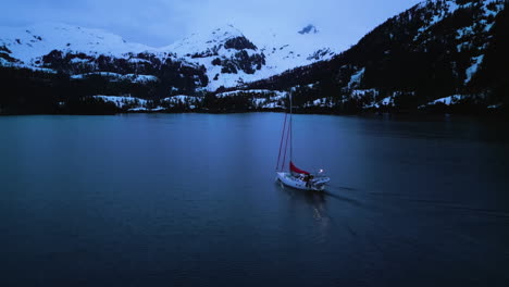 Drone-Siguiendo-Un-Velero-Moviéndose-En-Medio-De-Picos-Nevados,-En-La-Sombría-Alaska