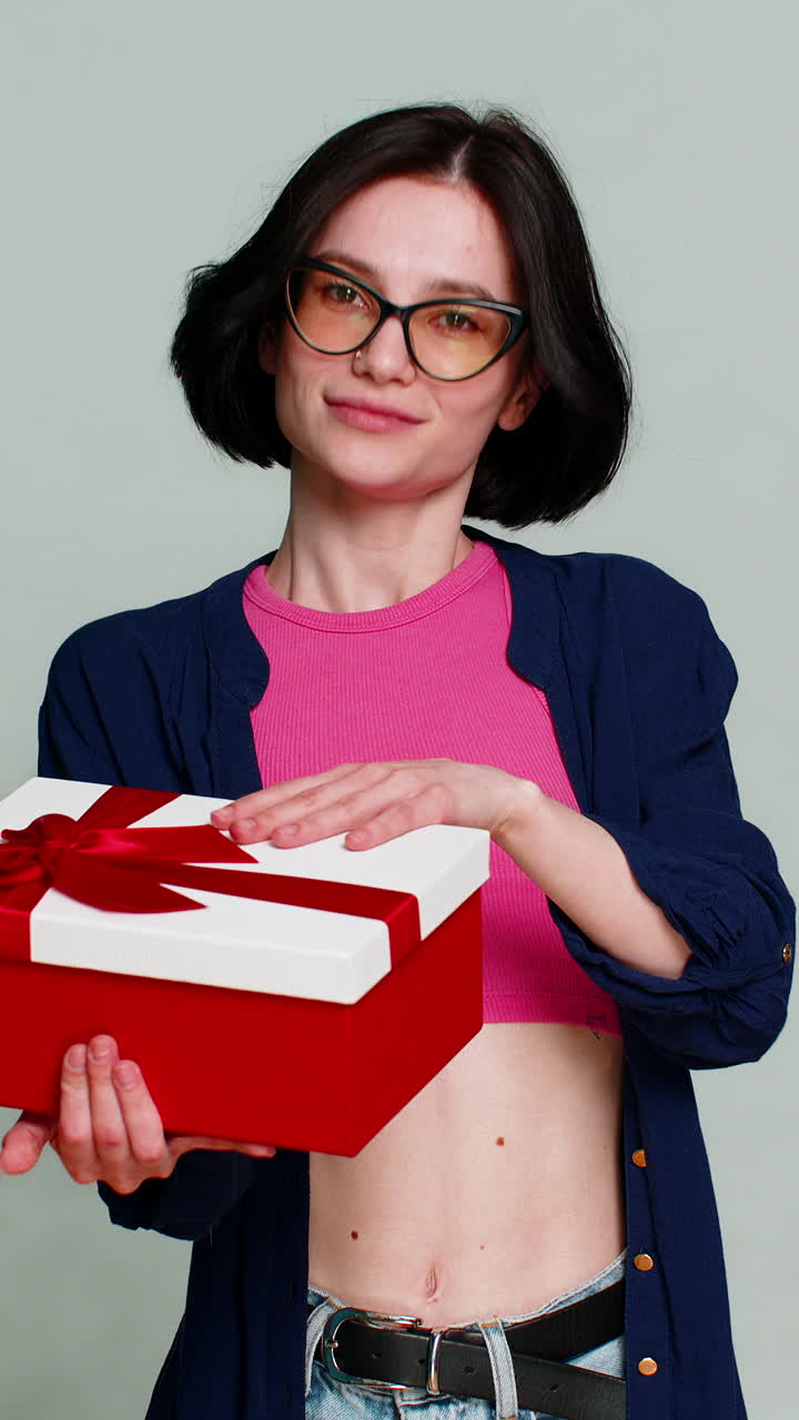 Woman mysteriously smiling extending hands forward holding gift box expressing surprise present