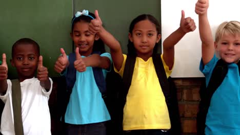 Cute-pupils-showing-thumbs-up-in-classroom