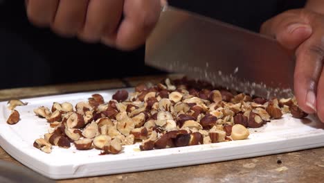 hands of an african american chopping hazelnuts with a knife - isolated