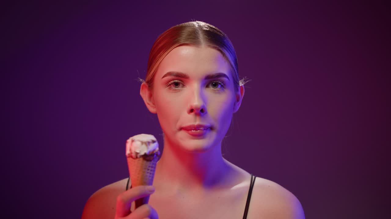 una hermosa mujer joven lamia un cono de helado, expresión sensual, toma de estudio