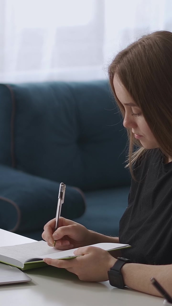 Focused Young Woman Taking Notes in a Notebook