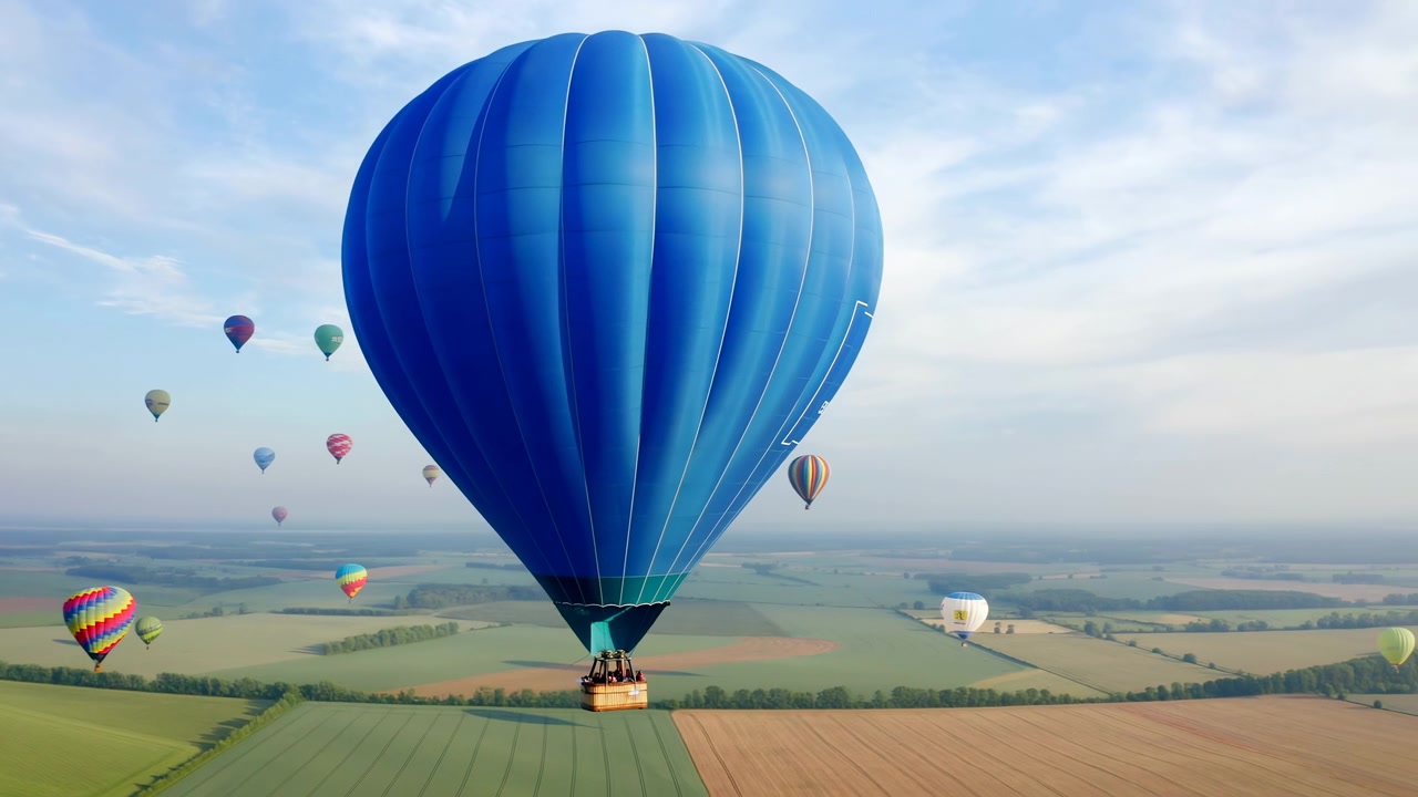 Pallone blu vibrante sopra campi agricoli all'alba, enorme involucro cobalto che fluttua sopra campi a mosaico