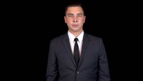 un joven empresario presenta una tarjeta bancaria verde. tarjeta verde chromakey. hombre en un traje negro sobre un fondo negro