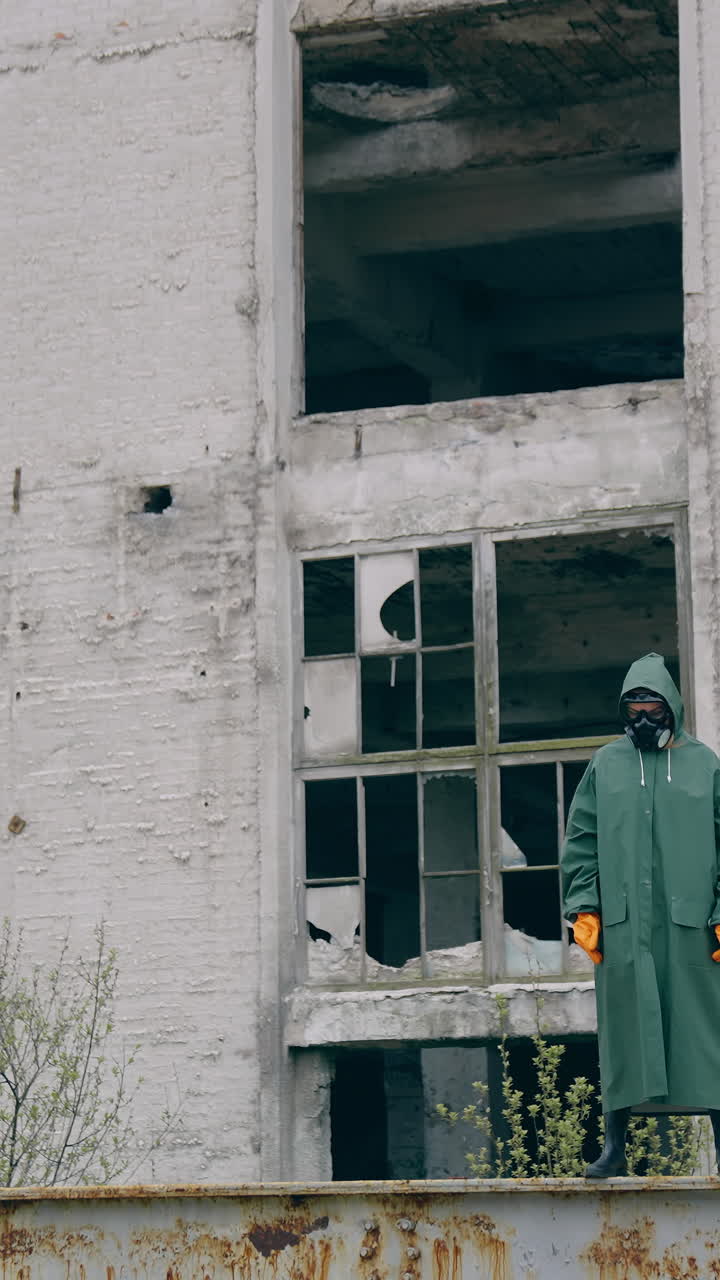 Stalker in military protective clothing. Lonely human in protective gas mask and military clothes walking on old factory