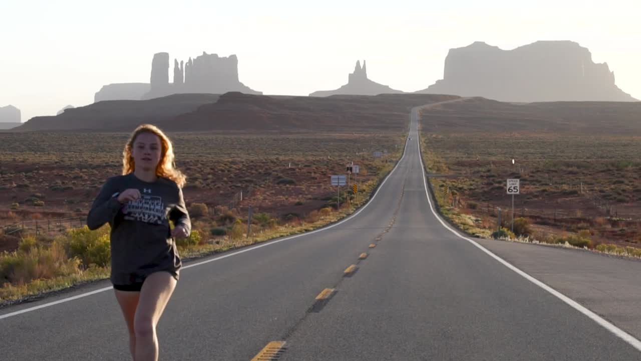 niña corriendo por una carretera desolada en el desierto oeste de estados unidos