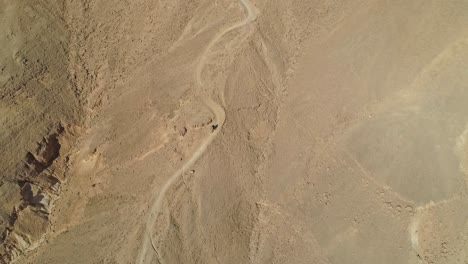 aerial footage of a group of extreme bicycle riders riding on downhill bike trails in the desert